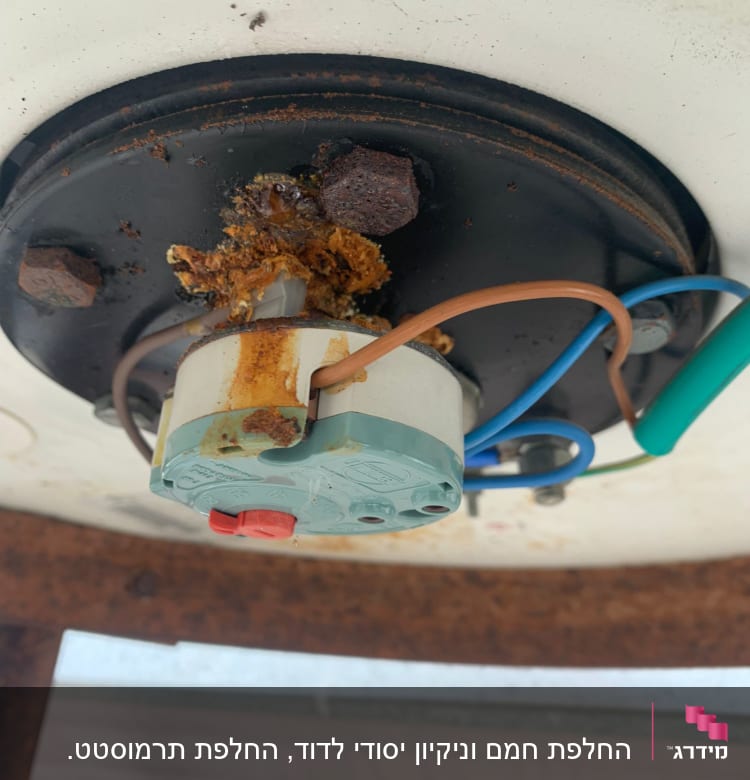 חלק תחתון של דוד שמש עם חלודה וחוטים חשמליים